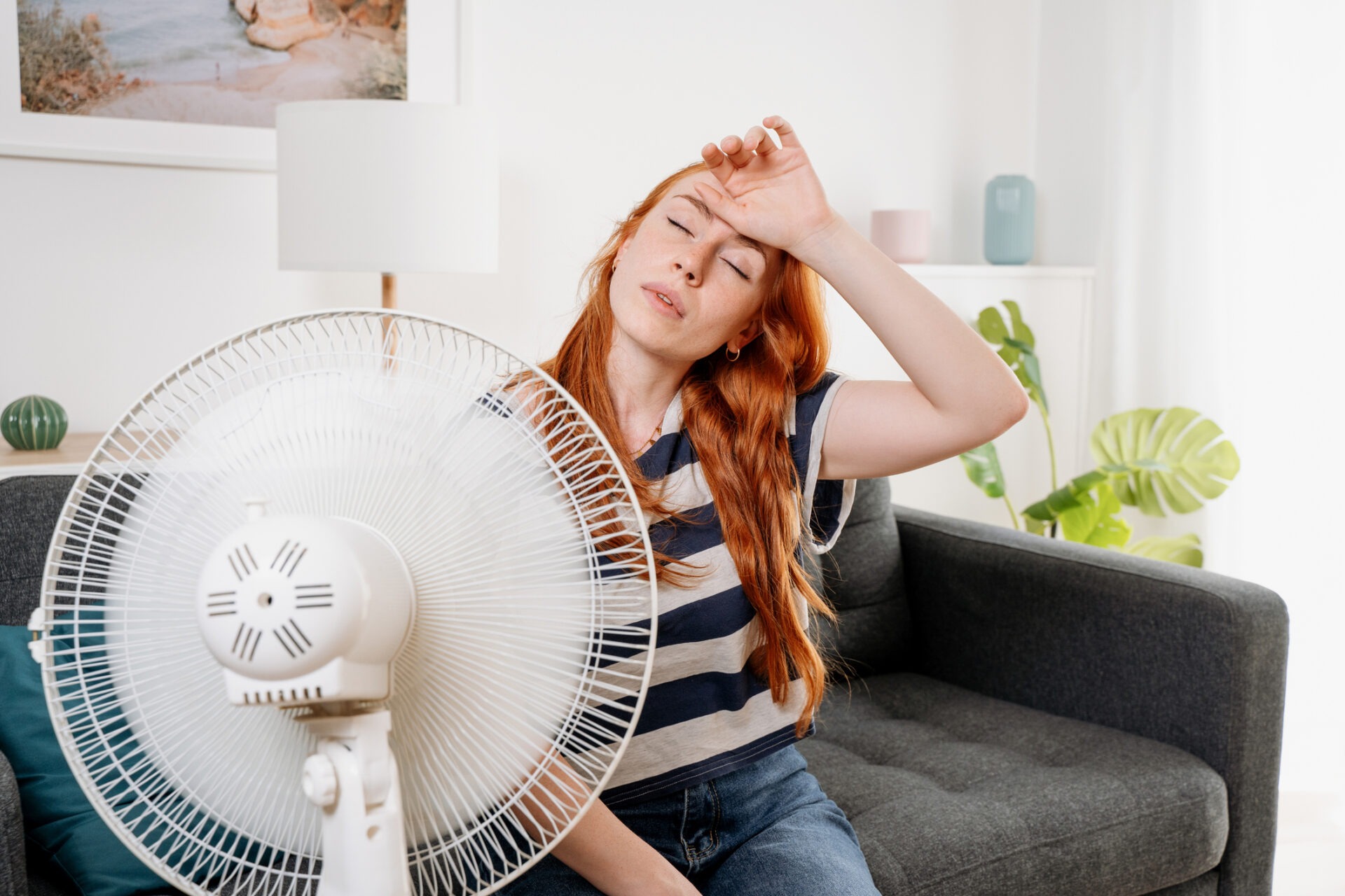 Overheated woman sitting on couch girl feeling unwell suffering from heating at home
